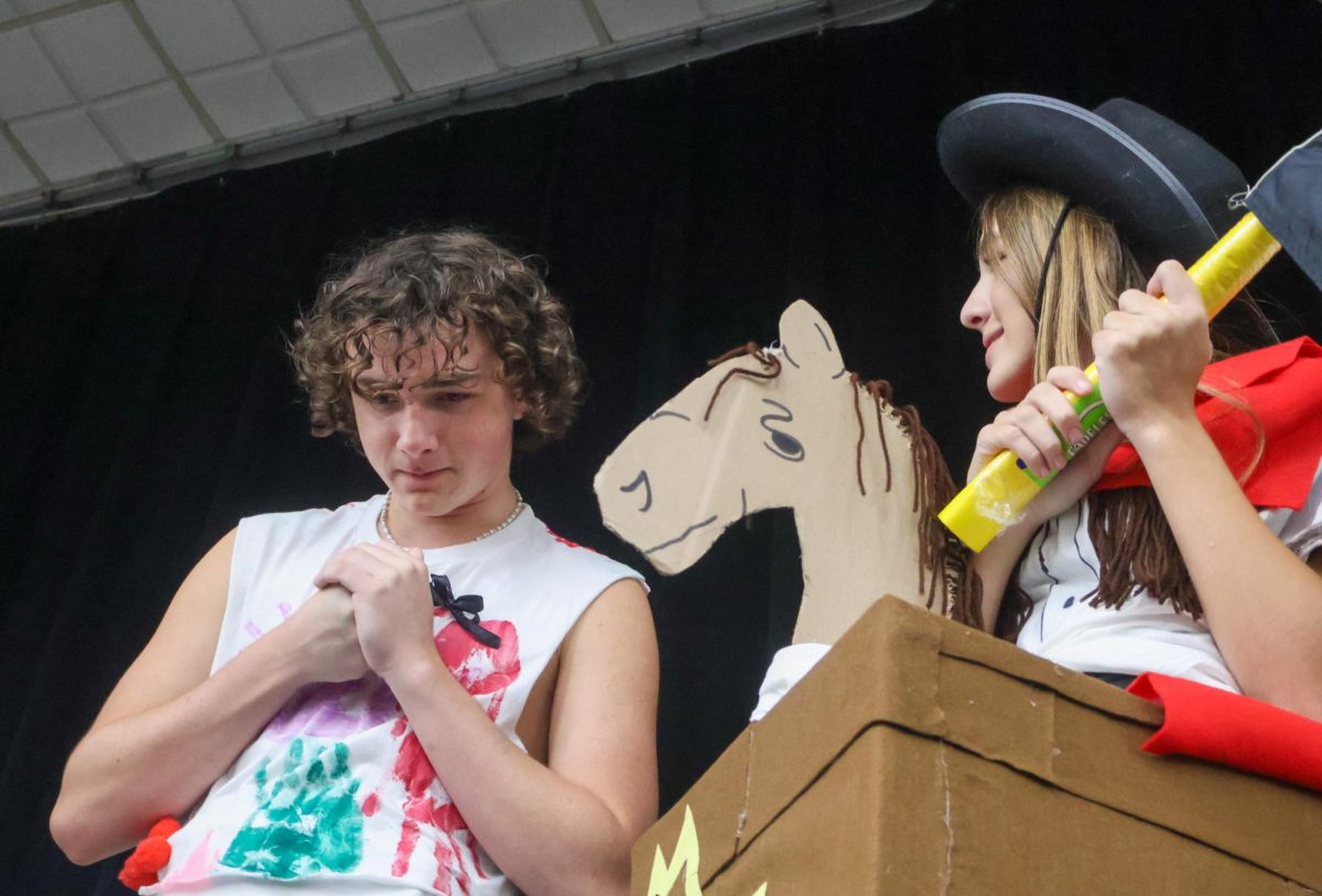 One School of the Arts and Sciences senior Dominic Ardolina and J.W Mitchell High School sophomore Taylor David discuss the fashion show while modeling on stage. 
