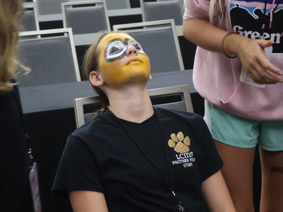 Lawton Chiles Middle School seventh grader Annabelle Baurhyte prepares for her team to continue painting her face as “Bart Simpson”.
