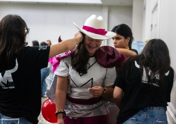 Wiregrass Ranch High School students pin maroon balloons and shiny decorations to their friend’s back, securing the bits and pieces of the costume before the show.