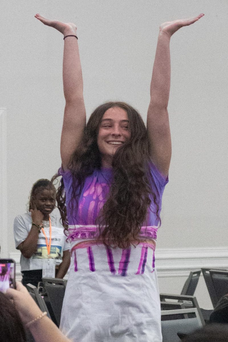 Angeline Academy junior Tessa Sevelius, who is adorned in a makeshift gown, raises her arms to the crowd to show off her outfit.