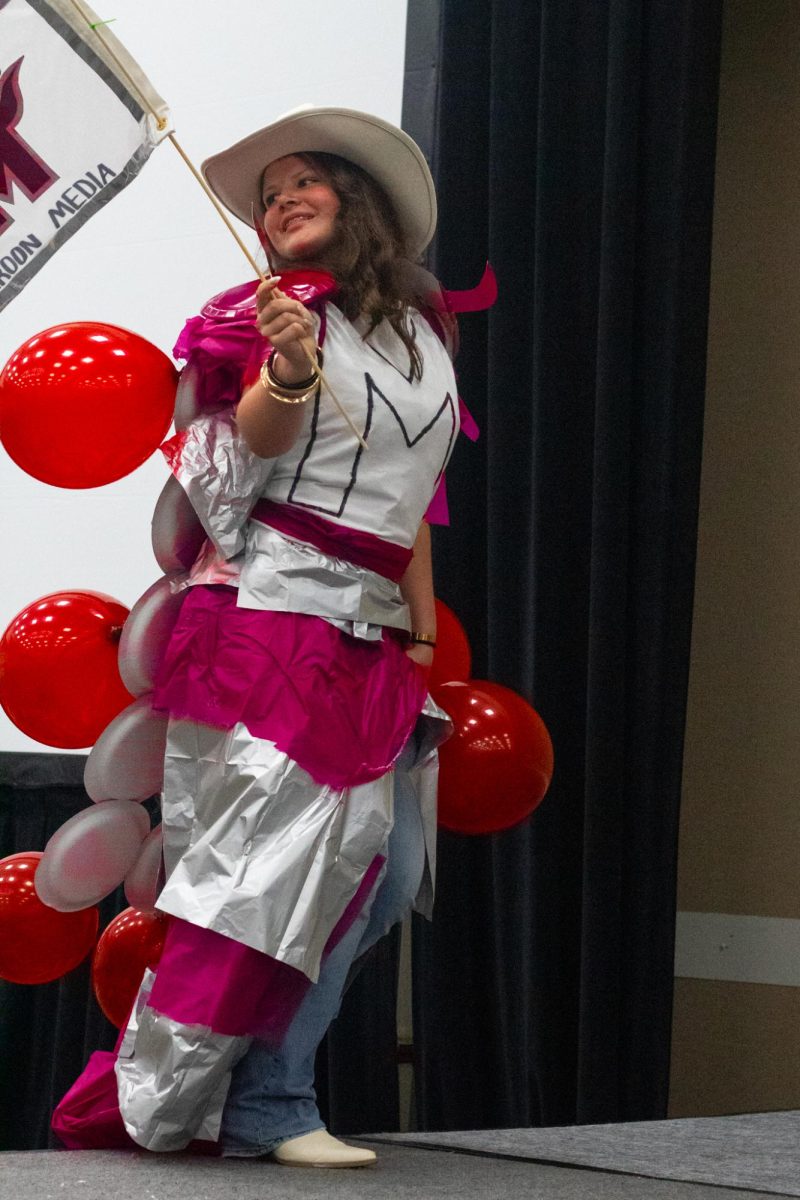 A Wiregrass Ranch High School student struts up the steps to the main stage in style, wearing pinned balloons and a spirited cowboy hat. 