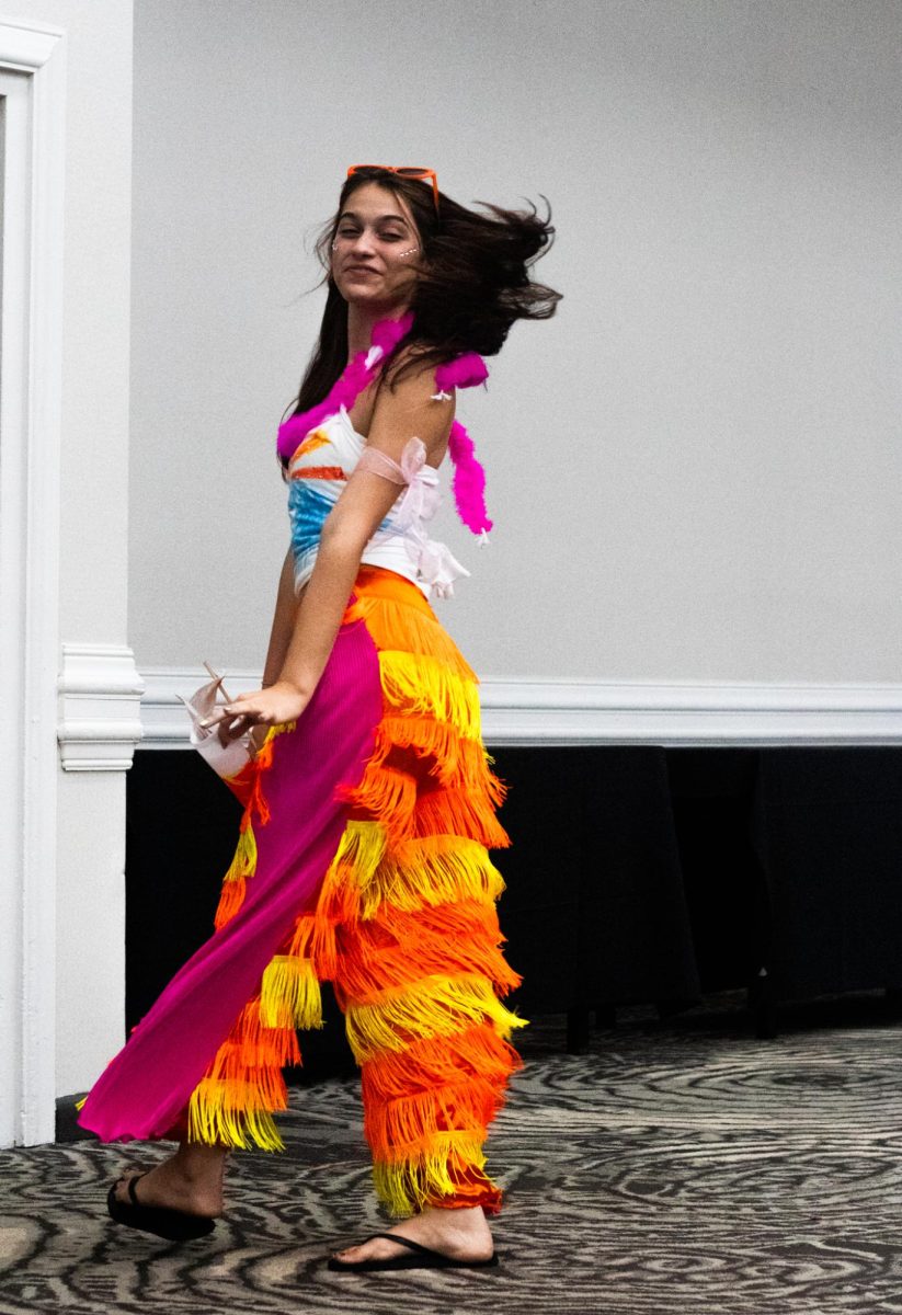 A festive student spins as the tassels she's wearing sway with her. Her colorful outfit matches her confidence on the runway.