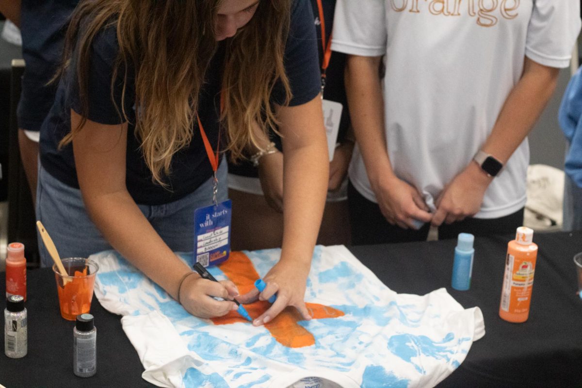Students from Boone High School work hard on their orange and blue spirit shirt. They've printed their own handprints across the shirt for a personal touch. 